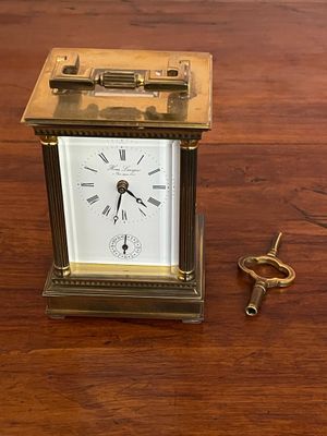 a small clock sitting on a wooden table next to a pair of scissors