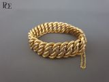 gros plan d'un bracelet en or avec une chaîne