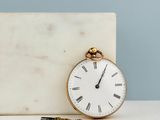 a white marble block with a gold pocket watch on it
