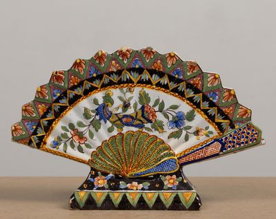 un éventail décoratif posé sur une table, orné de fleurs et d'oiseaux
