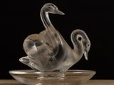 a glass swan figurine sitting on a glass plate