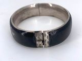 a close up of a black and silver bracelet on a white surface