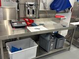 une grande table de travail en acier inoxydable équipée de deux bacs