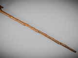 an old wooden walking stick on a gray surface