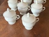 six white tea cups and a saucer on a wooden table