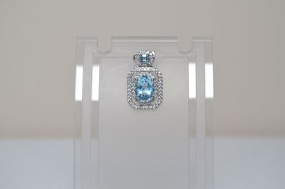 a clear display case with a blue topaz pendant on it