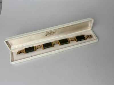 une photo représentant une paire de bracelets dorés et noirs dans un coffret blanc
