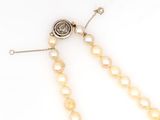 a close up of a necklace with pearls on a white background