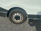 une camionnette blanche avec un pneu crevé, garée sur un parking