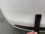 someone is measuring the height of a car ' s bumper with a ruler