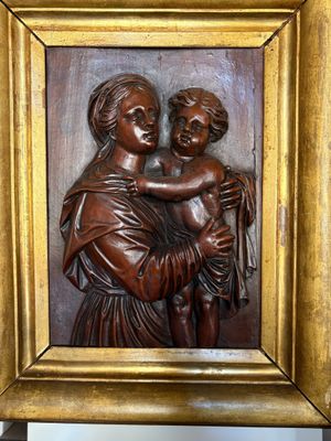 wooden relief of a woman holding a child in a gold frame