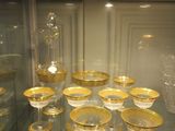 a glass display case with a lot of gold dishes