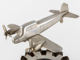 a silver model of a plane on top of a gear wheel