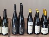 Des bouteilles de vin sont alignées sur une étagère devant un mur.