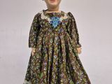 an image of a doll that is wearing a dress with flowers on it
