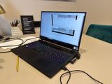 a laptop computer sitting on a desk with a pen and pencil