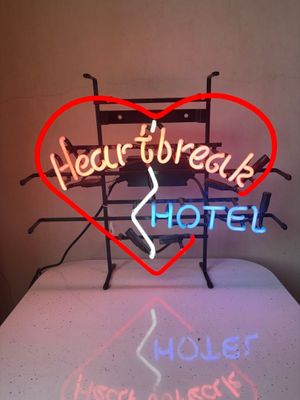 a neon sign that says heart break hotel on a table