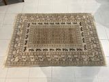 un tapis posé au sol au milieu d'une pièce, avec une chaise et une table en arrière-plan