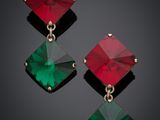 a pair of emerald and red earrings on a black background