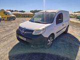 La camionnette blanche est garée sur un parking, avec d'autres véhicules en arrière-plan.
