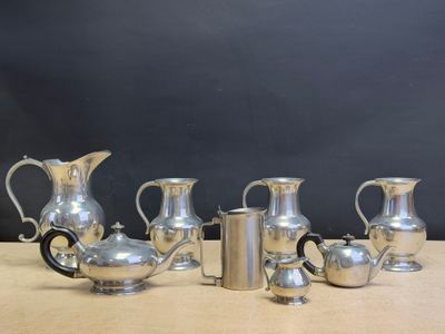five silver pitchers sitting on a table with a black background