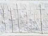 une plaque en pierre sur laquelle est gravée une croix, fixée sur le mur d'un immeuble
