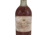 une vieille bouteille de vin posée sur une surface blanche