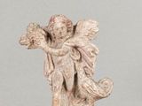 une statue représentant un ange assis sur une table en verre