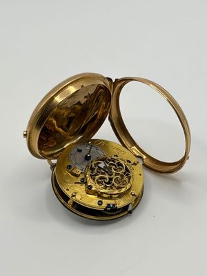 une vieille montre de poche posée sur une surface blanche