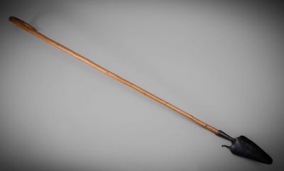 a close up of a wooden handled shovel on a gray background