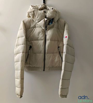 a white jacket hanging on a wall next to a coat rack