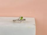une bague en tourmaline verte et diamants posée sur un bloc de marbre
