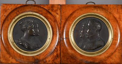 pair of antique bronze portraits of a man and woman on a wooden plaque