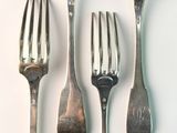 four spoons and a fork on a white surface