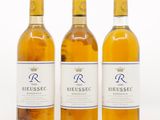 trois bouteilles de vin posées les unes à côté des autres sur une surface blanche