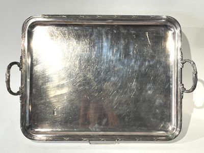 un plateau en argent muni de poignées, posé sur une table blanche
