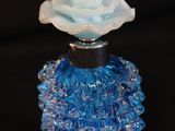 une bouteille en verre bleue contenant une fleur blanche
