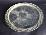une assiette en argent posée sur une table, sur fond noir