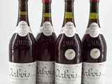 four bottles of wine are lined up on a white surface