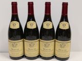 quatre bouteilles de vin rouge sont alignées sur une table