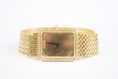 gros plan d'une montre en or sur une surface blanche