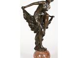 une statue en bronze représentant une femme tenant un oiseau, posée sur un socle en marbre