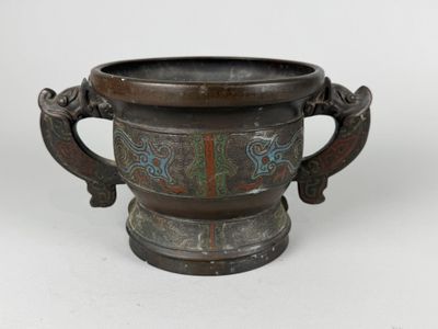 a metal vase with a handle on a white surface
