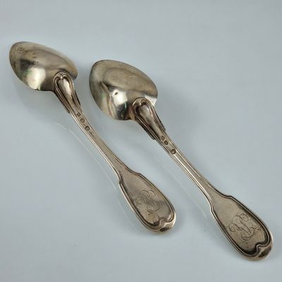 deux cuillères en argent et une cuillère posées sur une surface blanche