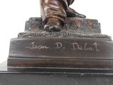 a bronze statue of a man sitting on a pedestal