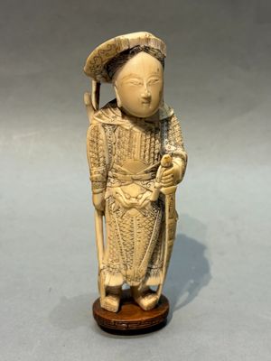 an antique carved ivory figurine of a woman with a hat and cane