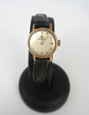 une photo d'une montre-bracelet posée sur un socle noir, sur une surface blanche