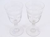 two clear wine glasses sitting on top of a white table