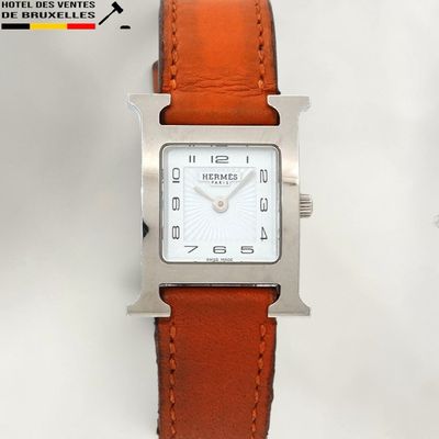 a silver watch with a brown leather strap on a white background