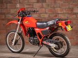 a red dirt bike parked in front of a brick wall